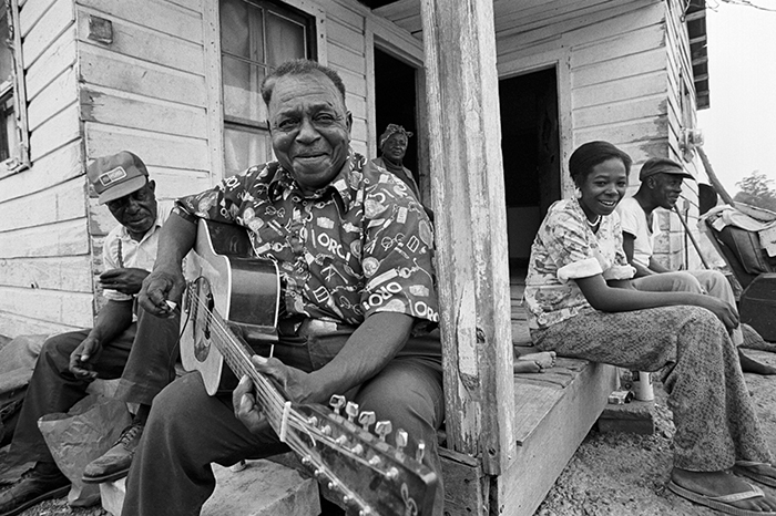 man playing guitar, people listening